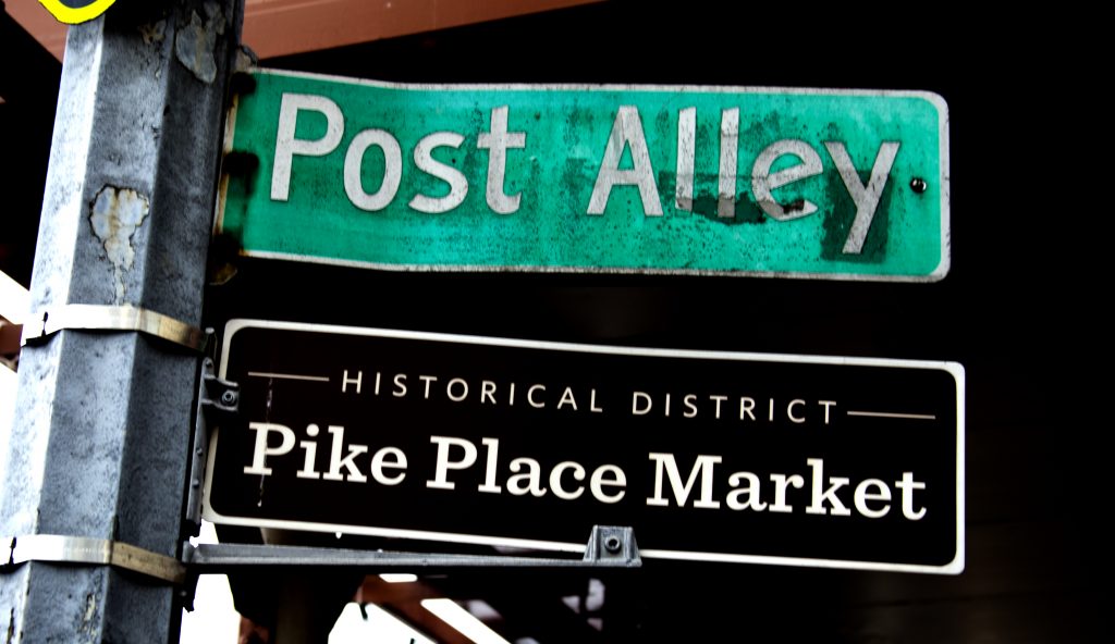 Two street signs: one that says Post Alley and one that says Historical District Pike Place Market