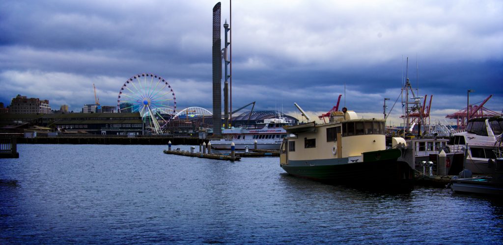 A view of the ocean, boats, and The Great Ferris Wheel in Seattle, WA