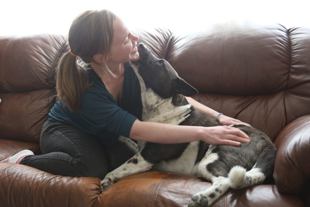 a woman sitting on the couch with a dog